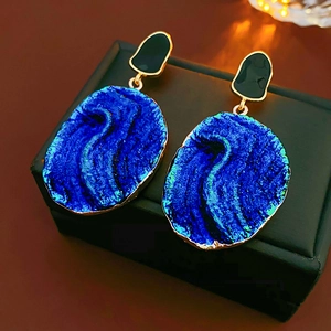 Detailaufnahme der Vintage-Ohrringe mit blauem Harz und edlen Goldrändern im Retro-Stil