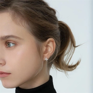 Close-up of S925 sterling silver cross earrings with zircons worn by a model
