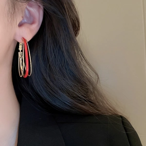 Close-up of model wearing red and gold multi-layered geometric oval hoop earrings