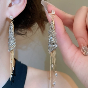 Macro shot of gold chain tassel earrings with sparkling grey square crystal accents