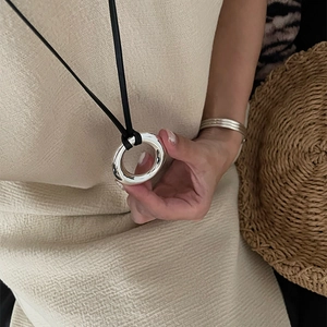 Minimalist polished silver circular ring pendant on black cord necklace in Y2K style