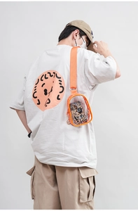 Detailed view of orange PVC transparent crossbody bag worn by a model in a studio setting