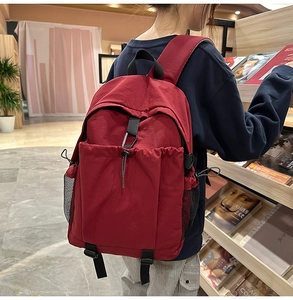 Detail eines burgunderroten Nylon Rucksacks mit Kordelzugtasche und Netzseitenfach