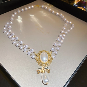 Elegant double-layered pearl necklace with golden bow and teardrop pearl pendant
