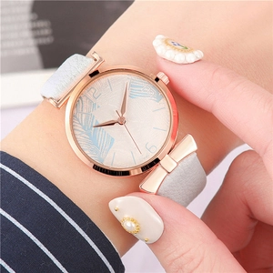 Detail of rose gold watch case with bow decor and feather pattern on the white dial