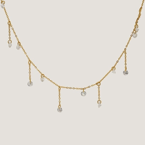 Elegant gold choker necklace with circular zircon tassel pendants on a warm white background