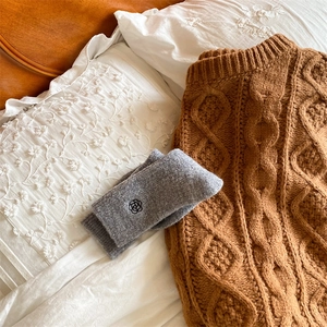 Close-up of grey wool blend socks with flower embroidery on a soft cable knit sweater