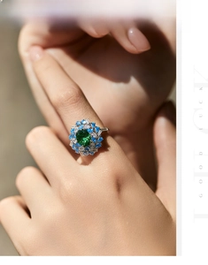 Close-up of vintage silver ring featuring a large emerald stone and blue sapphire accents