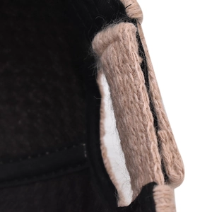 Close-up of beige knit baseball cap showing thick cable stitch texture and warm black lining