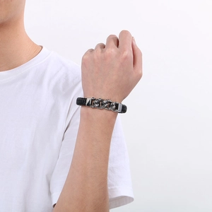 Détail d'un bracelet en cuir tressé noir avec crâne argenté sur le poignet d'un homme