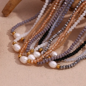 Beaded necklace with freshwater pearls, crystal beads, and gold accents on wooden stand