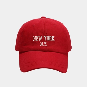 Detailed close-up of white 'NEW YORK N.Y.' embroidery on a red cotton baseball cap