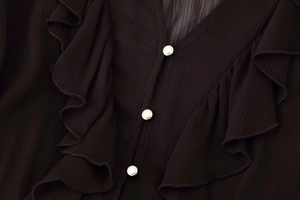 Close-up of V-neck pleated chiffon midi dress with silver buttons and ruffled texture