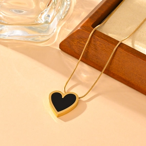 Elegante collana a cuore in acciaio al titanio dorato con intarsio nero su sfondo caldo