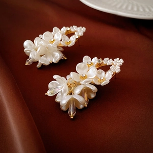 Detailed macro view of cream floral earrings with gold plating and crystal drops on silk