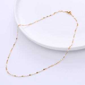 18-inch gold titanium necklace with white enamel beads on a white tray