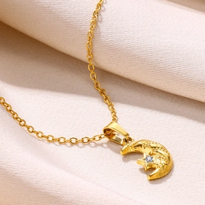 Macro shot of gold moon and star pendant with blue zircon on silk fabric