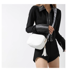 Close-up of white litchi pattern crossbody bag with geometric fabric strap and tassel detail