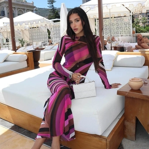 Women's long sleeve maxi dress featuring vibrant diagonal stripes in a beach setting
