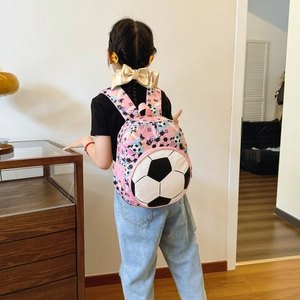 Pink children's soccer backpack featuring 3D football pocket shown on young girl's back