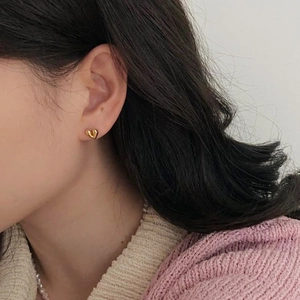 Elegant gold heart stud earrings in 14k plated S925 silver worn on an earlobe