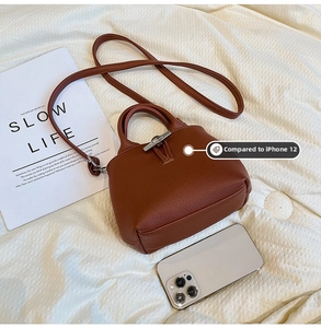 Brown bucket bag with litchi grain and bamboo clasp shown next to iPhone 12 for size