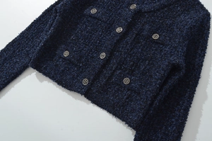 Dettaglio del tessuto tweed blu navy con bottoni dorati su un cardigan classico