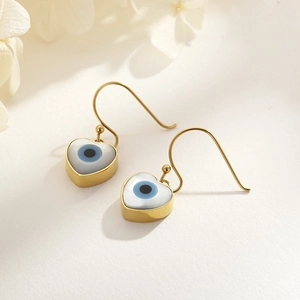 Close-up of heart-shaped evil eye earrings with gold hooks and floral decor