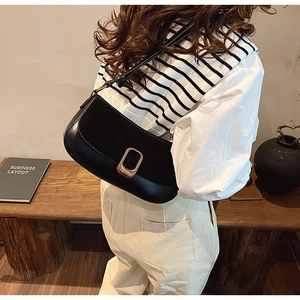 Minimalist black leather underarm bag featuring a stylish gold geometric metal buckle