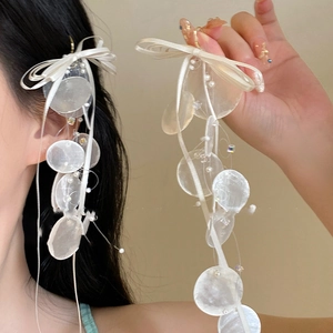 Detail of silk bow and shell tassel earrings with translucent beads and crystals