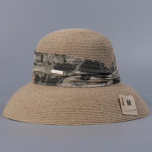 Detail of khaki woven straw hat with tie-dye ribbon band and brand logo metal tag