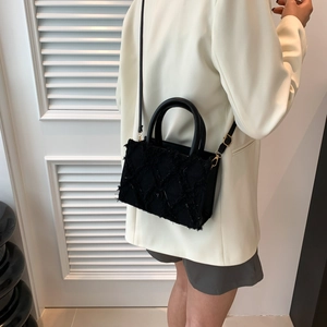 Black denim tote bag with frayed diamond pattern and adjustable shoulder strap