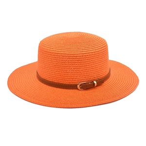 Detail of orange straw sun hat featuring a wide brim and decorative brown leather belt buckle