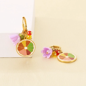 Close-up of lemon fruit slice earrings with colorful beads on a white geometric stand