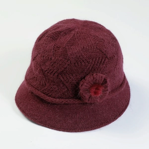 Detailed view of burgundy knit hat with decorative floral accents and soft fur pom-poms