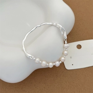 Detailed macro view of S925 silver lava-style frame and white baroque pearls on a ceramic dish