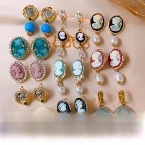 Detailed close-up of vintage cameo portraits and faux pearl drop earrings collection
