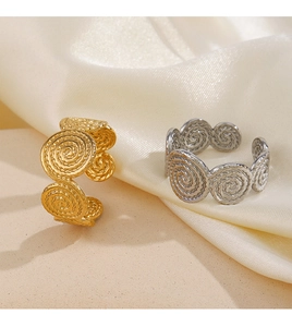 Detailed view of adjustable spiral texture rings in gold and silver on soft satin fabric