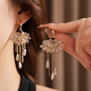 Close-up of champagne zircon fan earrings with gold fringe hanging on earlobe