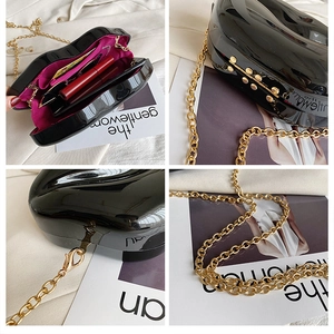 Detail of glossy black lip-shaped clutch bag showing purple lining and gold chain strap