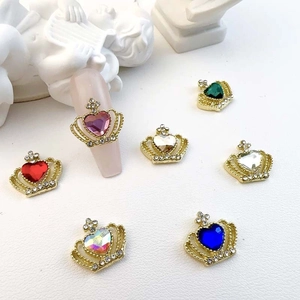 Macro detail of crown nail charms with colorful heart rhinestones on a golden base