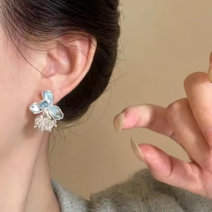 Elegant blue floral enamel stud earrings with crystal droplet cluster worn by a model