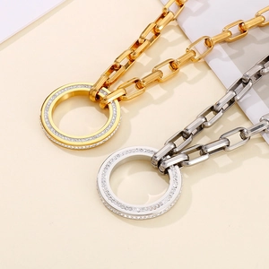 Detailed view of gold and silver chunky chain necklaces with crystal circle pendants