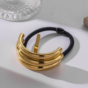 Detail of a curved golden stainless steel hair cuff with a black elastic hair band