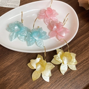 Détail de créoles en C avec fleurs en résine colorées et fini nacré sur plateau blanc