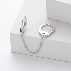 Detailed macro view of S925 silver handcuff earrings with connecting chain on white block