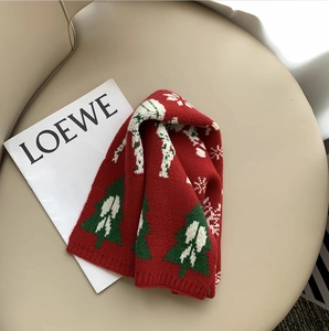 Detail of red knitted scarf with green Christmas tree patterns and white jacquard textures
