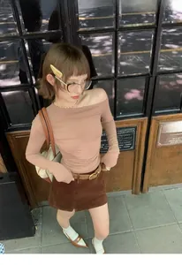 Detail of a brown corduroy mini skirt with a slim leather belt in a retro street style