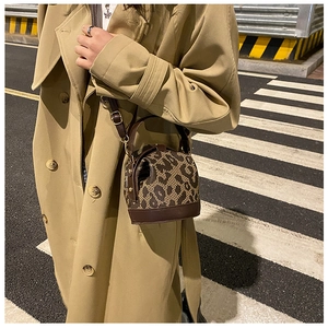 Close-up of leopard print cylindrical handbag with leather trim and gold metal hardware