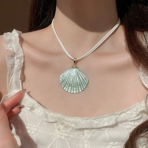 Close-up of light green shell pendant on a white rope chain necklace worn by a model